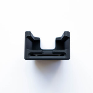 Close-up of a black plastic bracket or clamp with two prongs seen from below against a white background (top view).